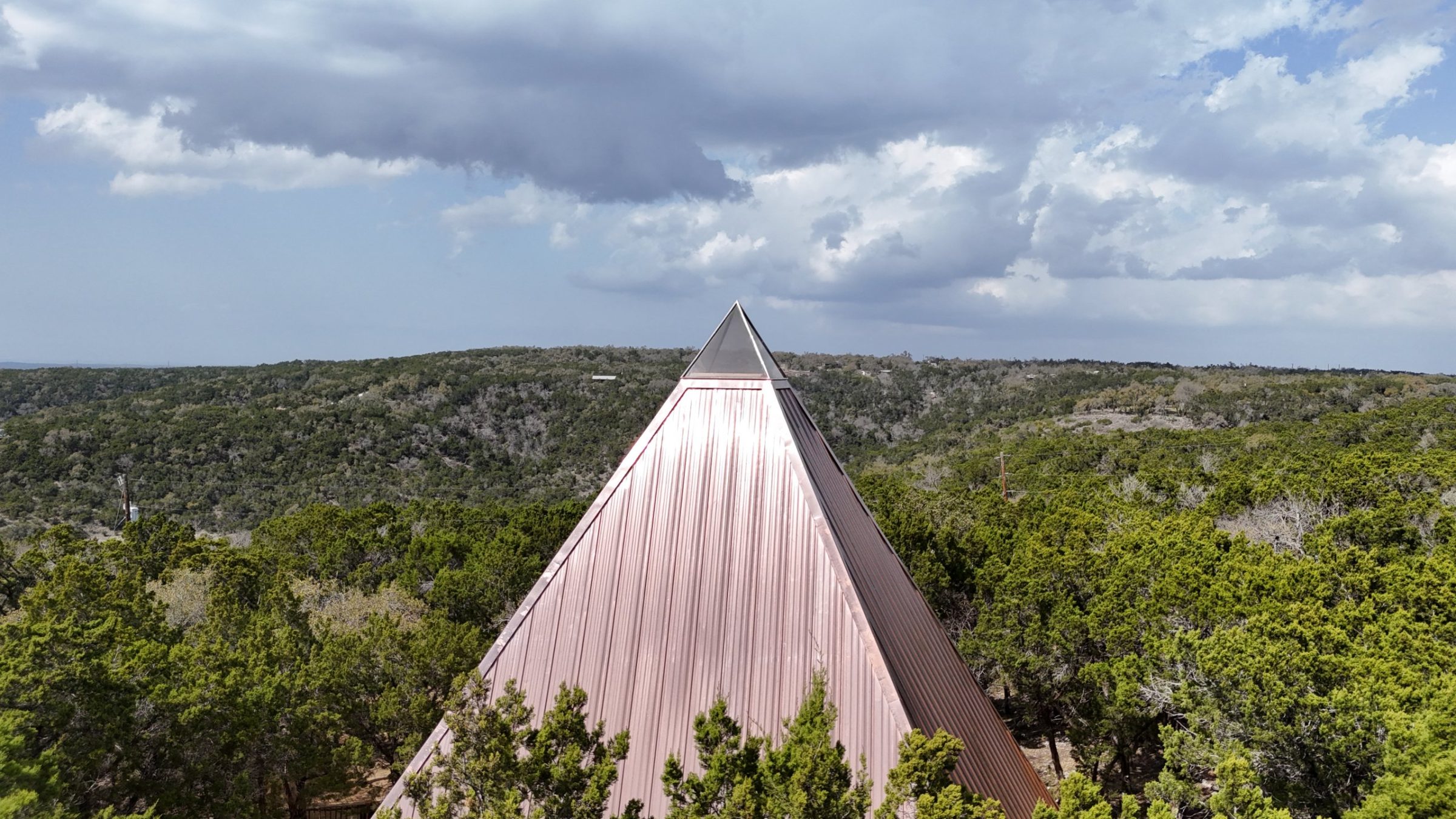 The pyramid apex rising above the oak canopy