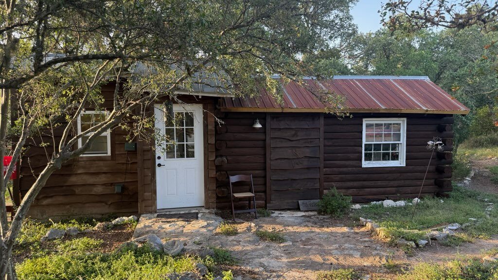 The Little Log Cabin with its dark log walls and rust-red tin roof