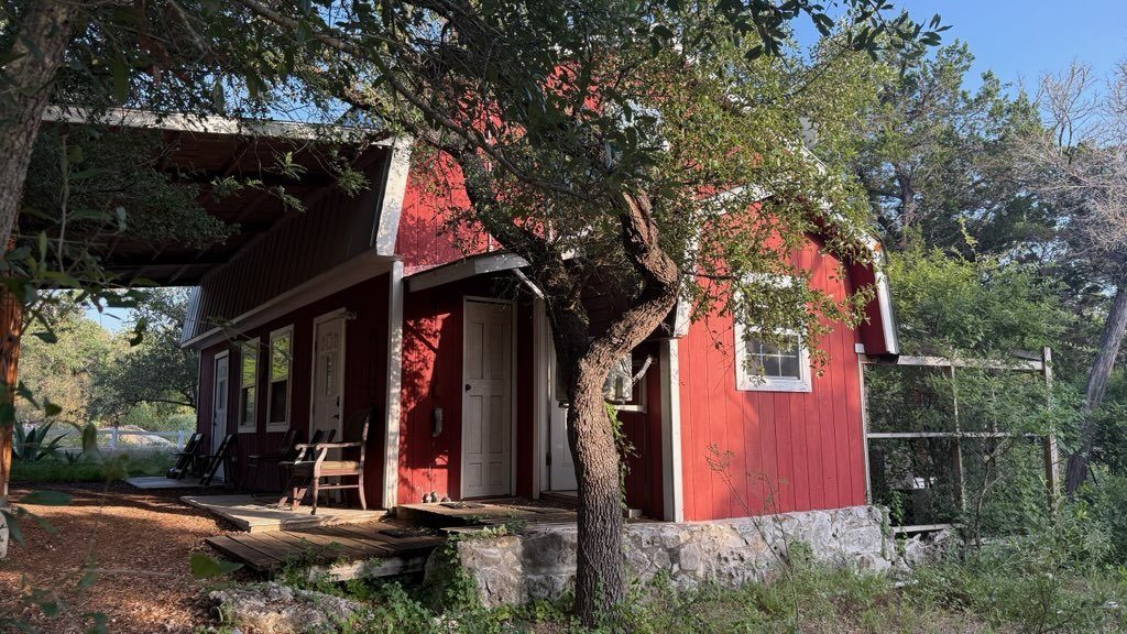 The Barn, painted deep red under an old oak tree
