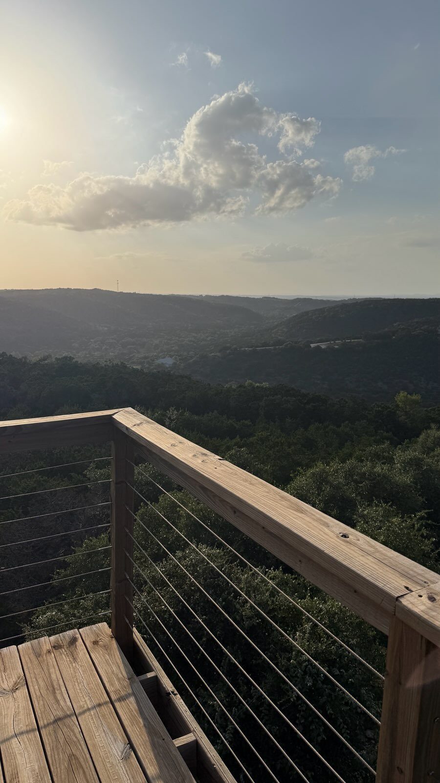 The valley turning gold beyond the deck rail in the last hour of light