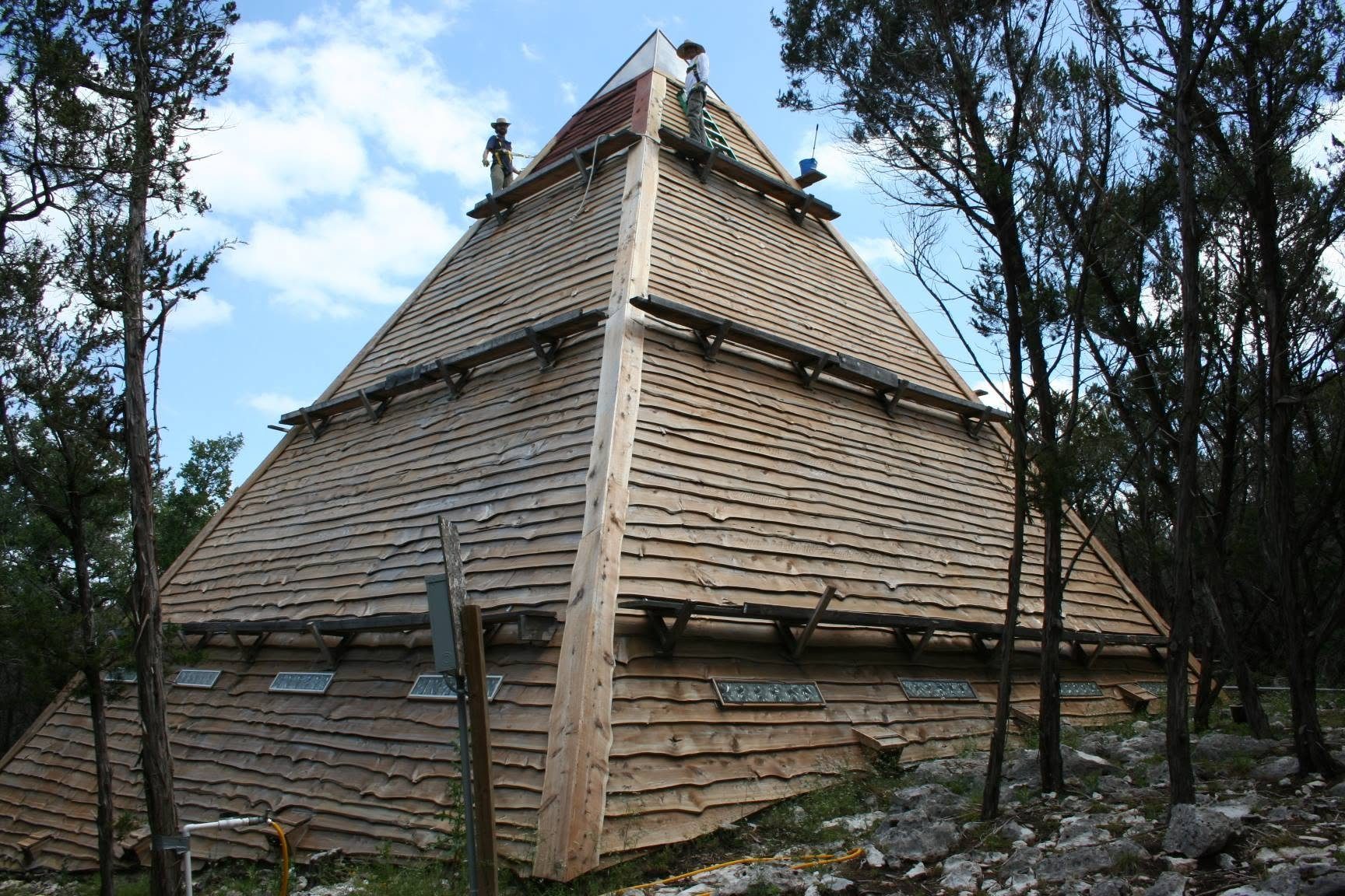 Crews working near the apex of the pyramid as the cedar shakes went on
