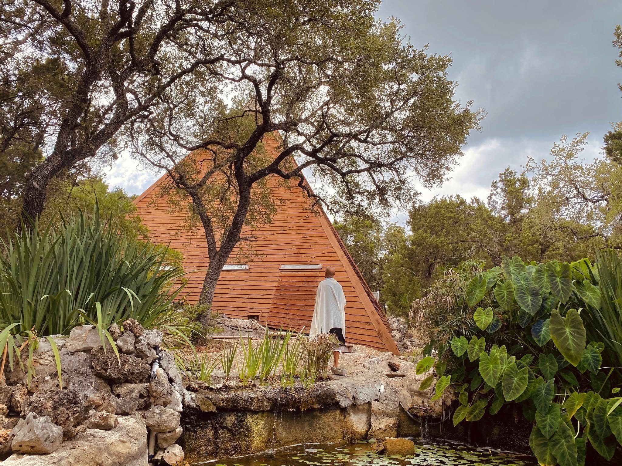 Walking the stone path past the grotto pond toward the pyramid