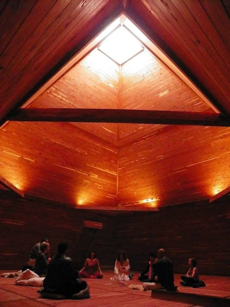 An early gathering seated in a circle beneath the pyramid skylight